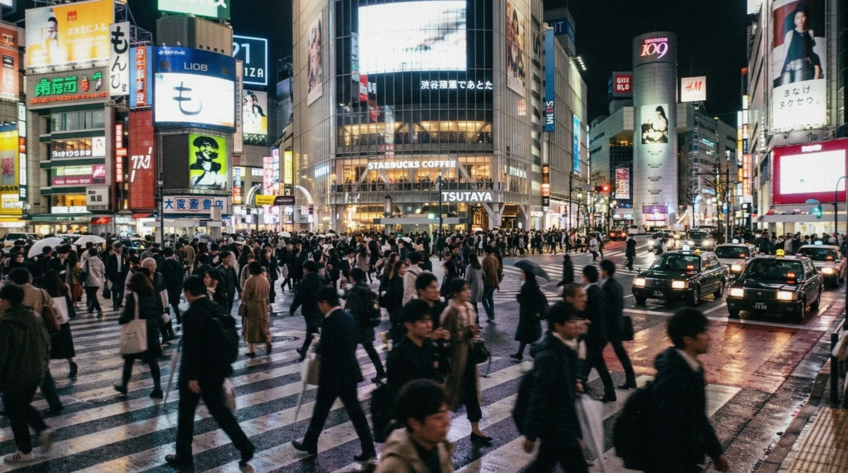 Crowds crossing the Shibuya Scramble under neon screens on an evening Tokyo city tour